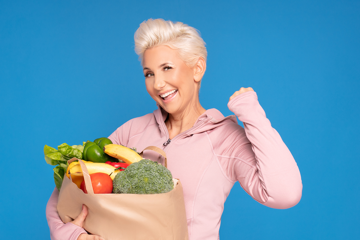 Woman holding shopping bag full of fresh food.